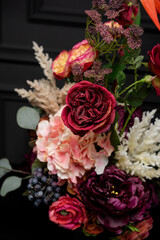 Plastic handmade bouquet artificial flowers composition.Beautiful flowers in vase on a table with black  background. Women's, mother's day. Spring, summer season. Front view.Selective focus.
