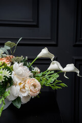 Plastic handmade bouquet artificial flowers composition.Beautiful flowers in vase on a table with black  background. Women's, mother's day. Spring, summer season. Front view.Selective focus.
