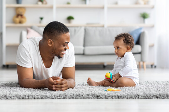 Young Happy African American Dad Playing With Cute Infant Baby At Home