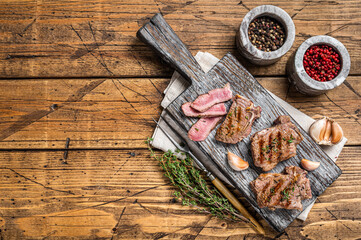 Roasted in BBQ lamb loin chops steaks, cutlets on a wooden board with herbs. Wooden background. Top view. Copy space