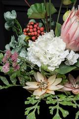 Plastic handmade bouquet artificial flowers composition.Beautiful flowers in vase on a table with black  background. Women's, mother's day. Spring, summer season. Front view.Selective focus.
