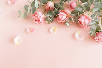 Flowers background.Pink roses  and eucalyptus branch bouquet frame top view on pink background with copy space.  