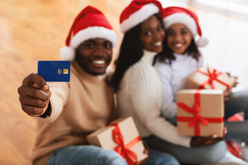 Xmas Shopping. Smiling black family holding showing credit card