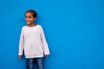 Smiling kid boy portrait. Little african american child boy posing on blue background, wall.