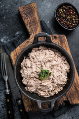 Duck pate Rillettes de Canard in a pan with greens. Black background. Top View