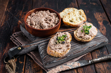 Toasts with Duck pate Rillettes de Canard on wooden board. Dark wooden background. Top View