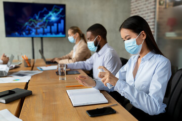 New Normal. Asian Female In Face Mask Using Disinfectant Spray In Office