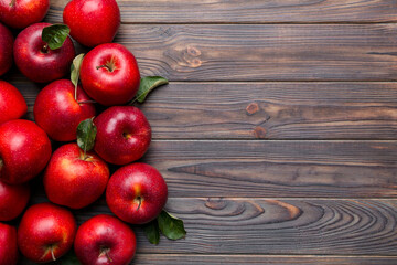 Fresh red apples with green leaves on wooden table. On wooden background. Top view free space for...