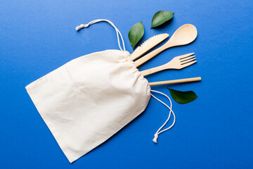 Eco friendly reusable recyclable white eco bag with kitchenware on Colored background. Concept zero...