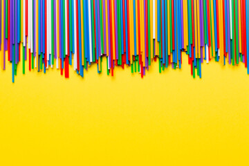 Heap of colorful plastic drinking straws on Colored background, flat lay. Copy Space for text