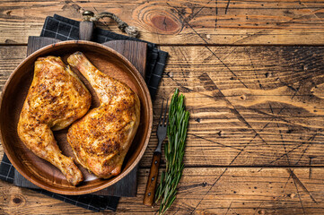 BBQ Grilled chicken legs in a wooden plate with herbs. wooden background. Top view. Copy space