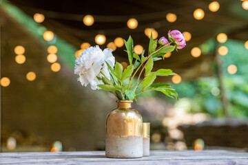 Flower in a vase at a table as wedding decoration with lights twinkeling in the background