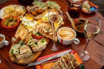 Class of cava on a table full of food, tapas, drinks, coffee at a restaurant