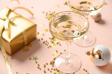New Year champagne in wine glasses and Christmas gold gift on pink background. Close up.
