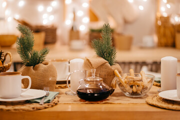 a teapot on the table in decorated kitchen for new year. electric garlands.