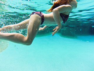 Young girl swimming underwater at a pool