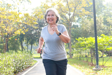 Asian elderly woman jogging in the park in the morning she smiles happy Healthy body. concept of...