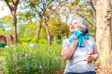 Asian elderly woman exercise in the park in the morning she smiles happy Healthy body. concept of health care for seniors to be healthy. Copy space