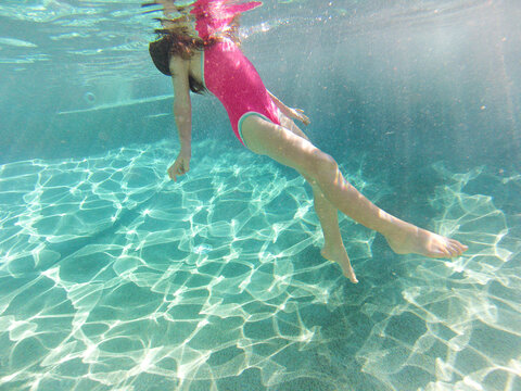Young girl swimming underwater at a pool