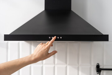Woman's hand turning on hood in kitchen after repair