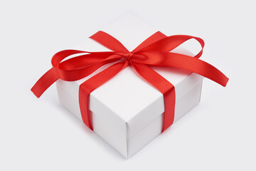 White gift box with red ribbon bow, isolated on white. White box with red ribbon. Gift for Christmas, New Year, Birthday, Valentine's Day. 