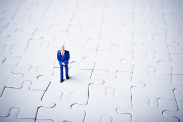 businessman miniature figurine standing on a blank puzzle