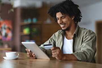 Online Shopping. Black Guy Using Digital Tablet And Credit Card In Cafe