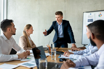 Male boss discussing company strategy with colleagues during corporate meeting in office