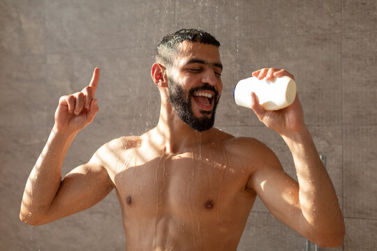Young man washing body singing in shampoo bottle