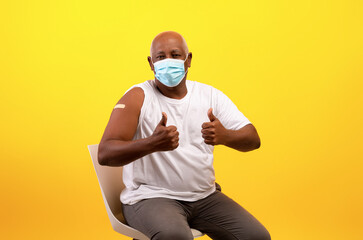 Vaccinated senior black man with band aid plaster after anti covid vaccine shot showing thumbs up gesture - obrazy, fototapety, plakaty