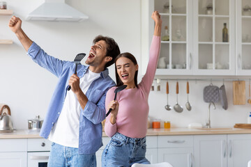 Satisfied happy millennial caucasian male and female sing at imaginary microphone, enjoying dance