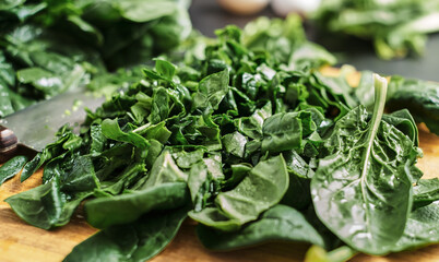 Juicy green sliced spinach leaves lie on a wooden cutting board. Selective focus, close-up of...