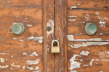 old ruined wooden door with closed padlock