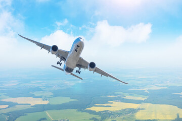 Flying passenger jet plane over fields and forests.