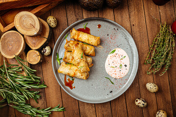 Turkish cigar shaped rolls boreks with sauce on wooden background