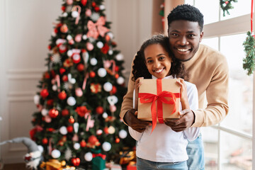 Happy black family celebrating Christmas holding gift box