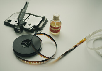 Vintage 8mm moviola cutter with 8mm reel and glue on white background.