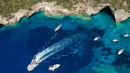 Obraz premium Aerial drone photo of paradise bay an caves of blue lagoon in beautiful island of Paxos visited by yachts and sail boats, Ionian, Greece