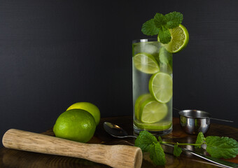 Glass of Mojito cocktail with mint and lime on a black board wit