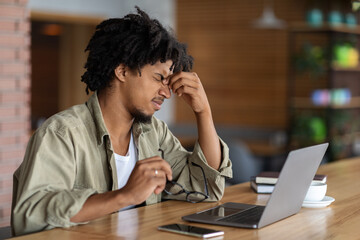 Obraz premium Eye Strain Concept. Black Guy Tired After Working On Laptop At Cafe