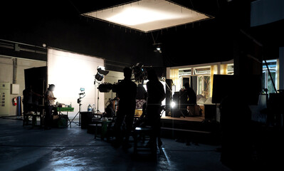Video recording. Behind the scenes of silhouette people working in big production studio with...