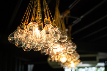 Row of beautiful bunch ceiling lightbulb set during glowing in warming light shade. Interior decoration object photo. Close-up and selective focus at foreground.