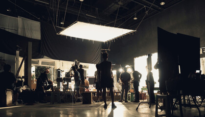 Video recording. Behind the scenes of silhouette people working in big production studio with...