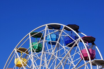 Colorful fair ferris wheel over a blue sky on a sunny day.