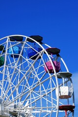 Colorful fair ferris wheel over a blue sky on a sunny day.