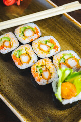 Traditional Japanese rolls with shrimps and vegetables on a plate with wooden chopsticks