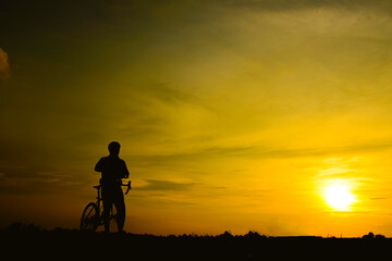 Obraz na płótnie Canvas Silhouette of handsome man riding bicycle on sunset,sport man concept,Fill flare effect