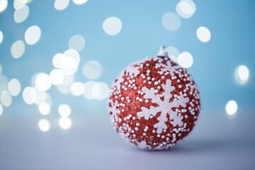 Red Christmas ball on blue background with festive bokeh lights, holiday card template