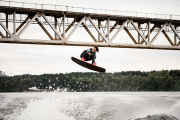 young woman makes extreme jump on wakeboarding, there are a lot of splashes water around
