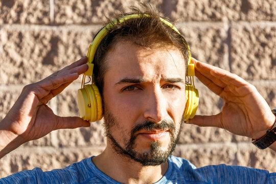 big close-up view millennial caucasian man putting on headphones and looking to the camera